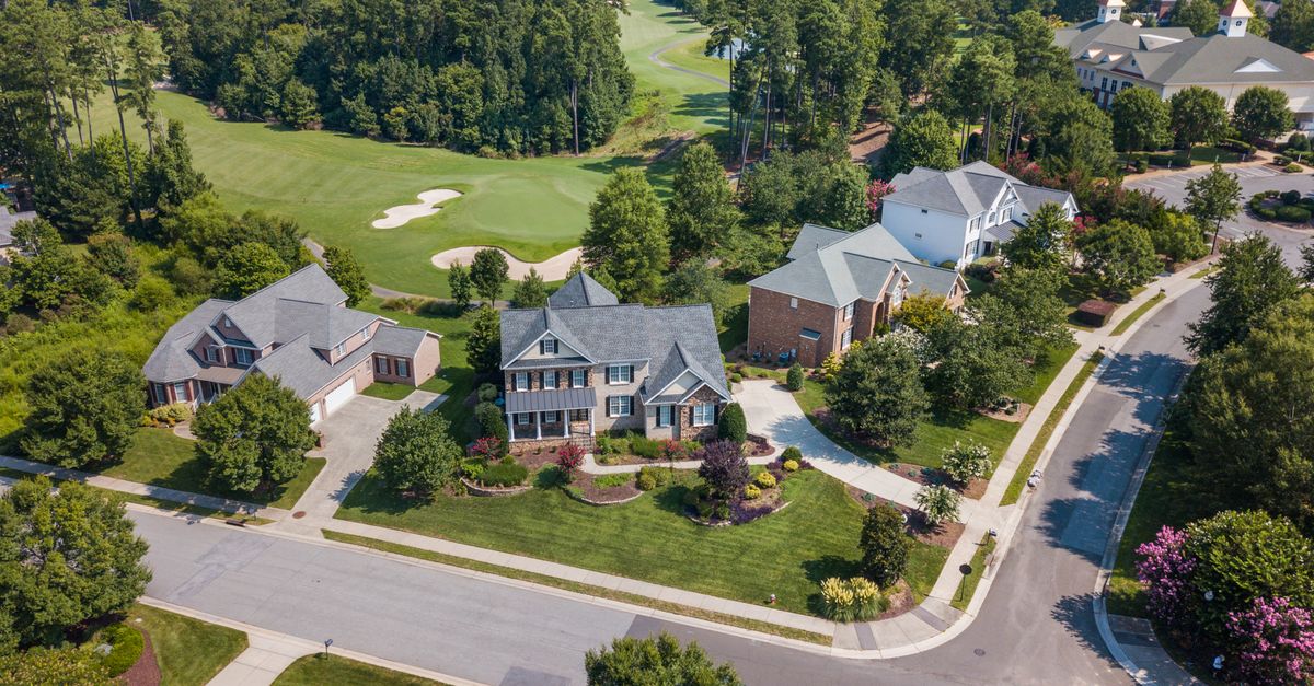 Aerial view of suburban neighborhood with lush greenery and golf course in Raleigh, NC.