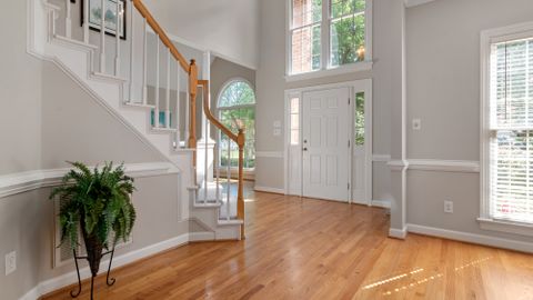 Elegant entrance with a wooden staircase and large windows, perfect for modern interiors.