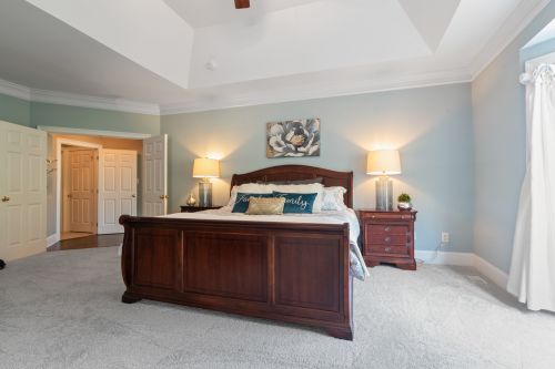 Free Spacious and elegant bedroom featuring a classic wooden bed, soft carpeting, and tasteful interior design elements. Stock Photo