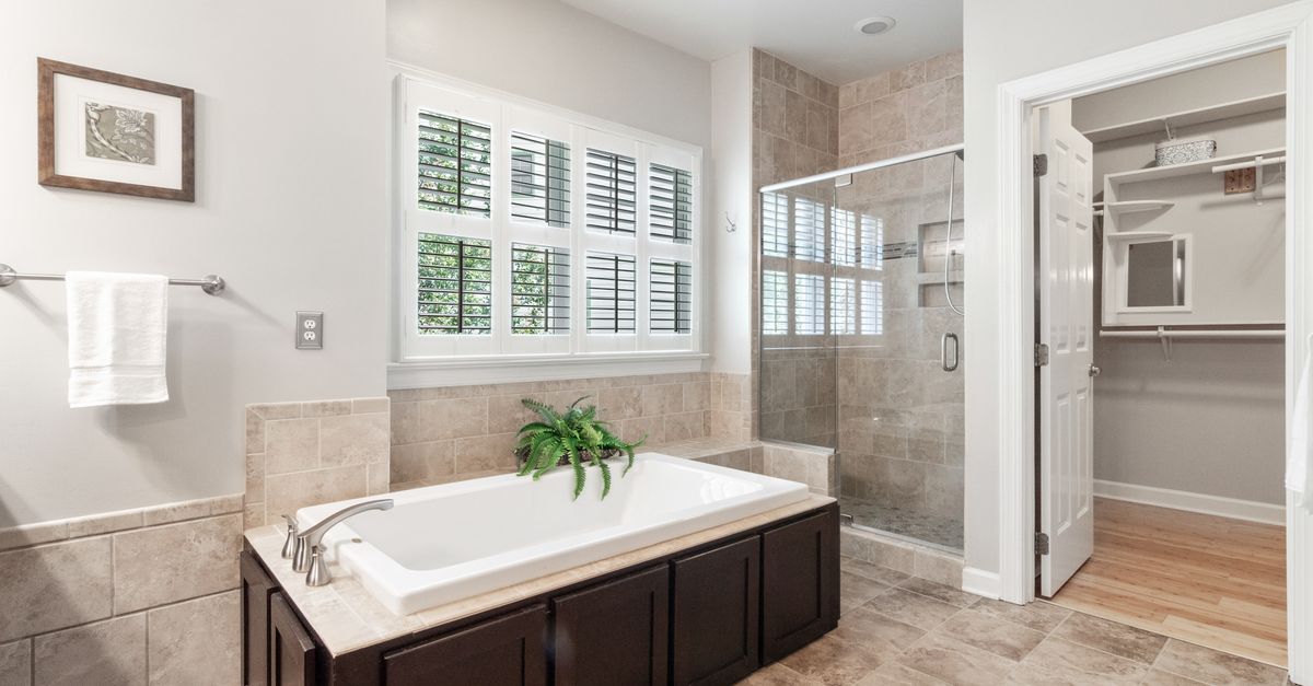 Bright and airy bathroom featuring a bathtub, shower, and natural light from windows.