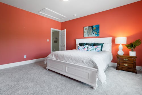 Free White Bed With White Bed Linen in an Orange Bedroom Stock Photo