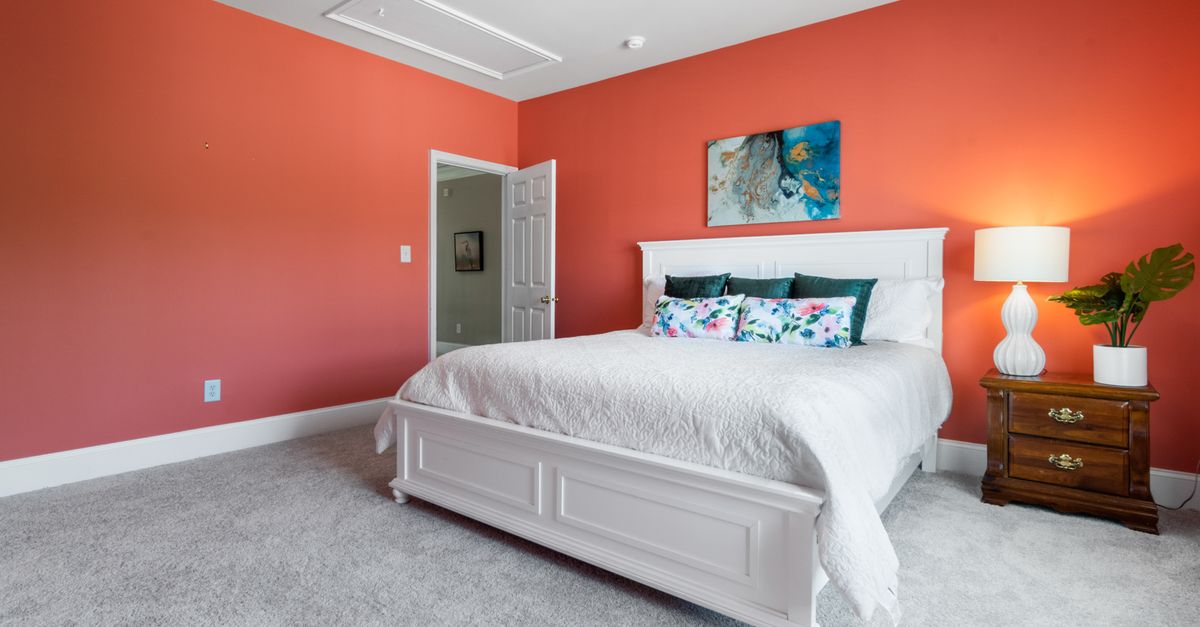 Stylish bedroom featuring a coral accent wall and elegant white furniture.
