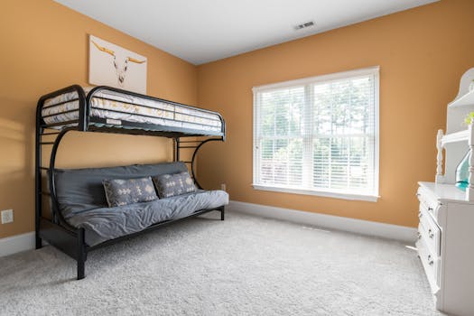 A bright bedroom with a modern bunk bed, large window, and stylish decor.