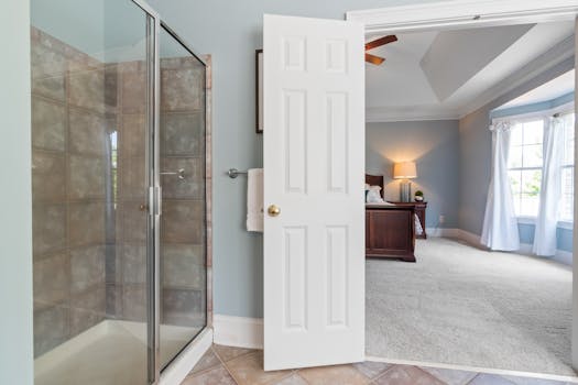 Spacious and elegant home interior featuring a bedroom and bathroom with glass shower, natural light, and luxury design.