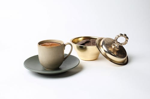 Cup of Coffee Beside a Gold Container