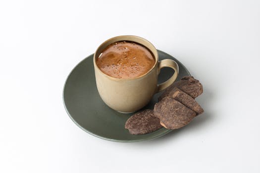 A steaming cup of coffee served with chocolate slices on a green saucer, perfect for coffee enthusiasts.