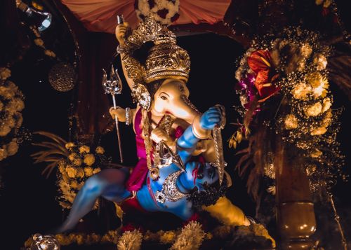 Free Colorful Ganesh idol surrounded by flowers and decorations in a traditional Indian setting at night. Stock Photo
