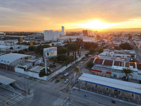 Aerial view of Mexico City's urban landscape at sunset, showcasing modern architecture in a warm glow.