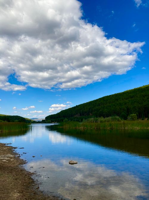 Free Tranquil rural landscape with serene lake reflection under a cloudy sky. Stock Photo