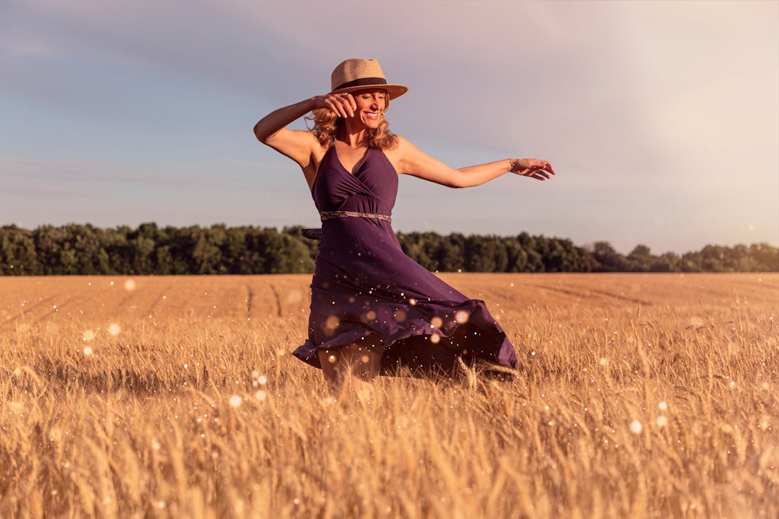 Woman in Brown Hat Standing on Wheat Field