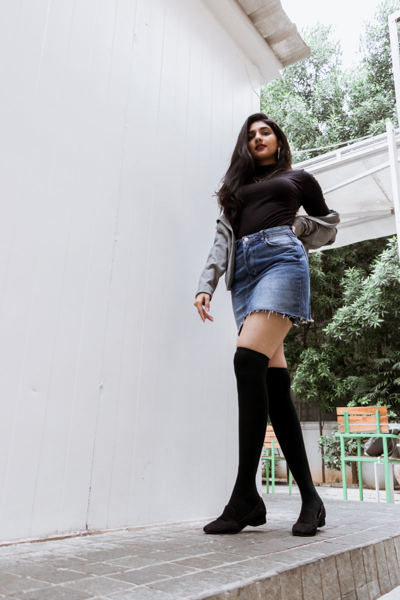Woman in black top, denim skirt and knee-high boots