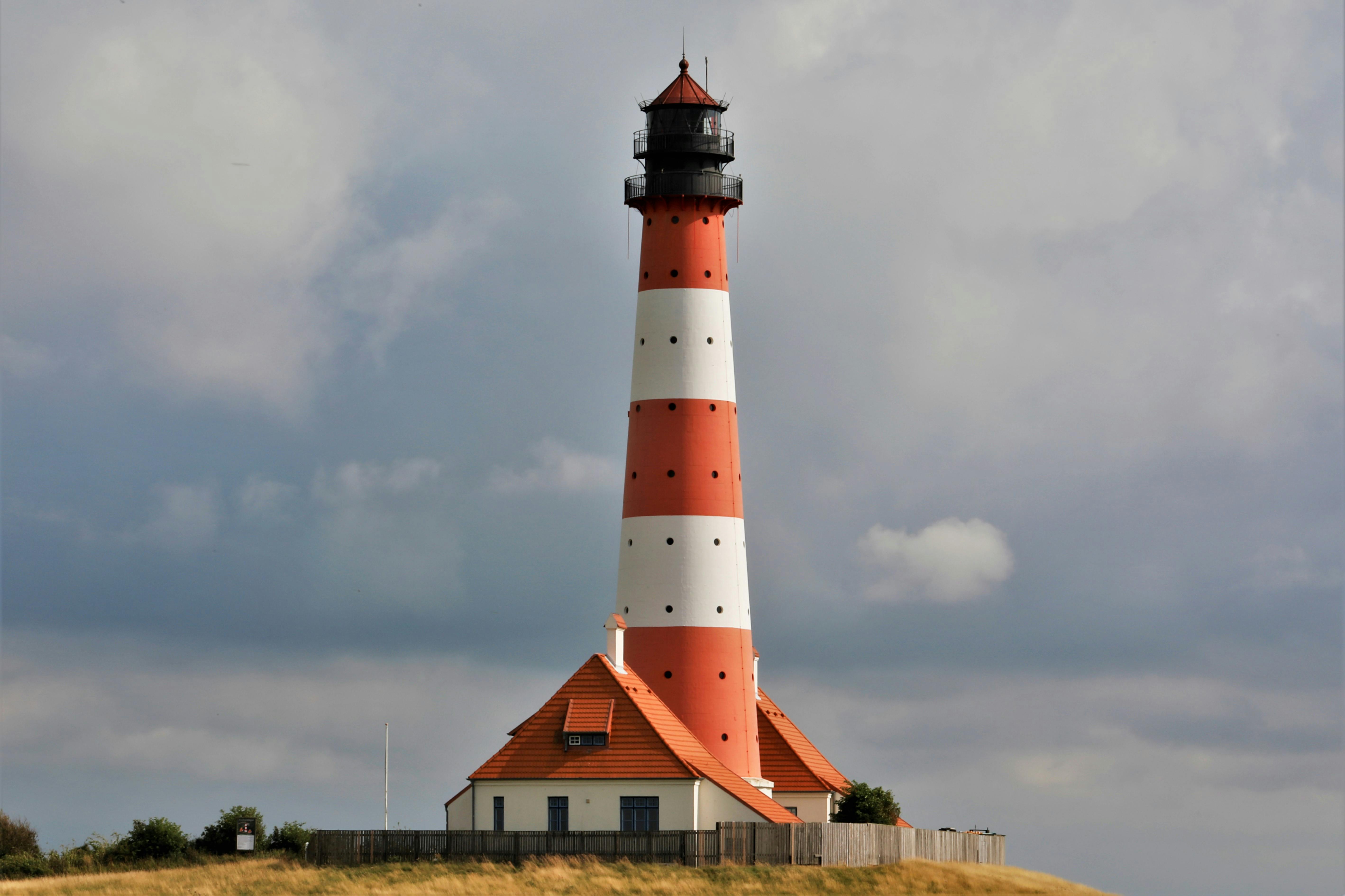 Red and White Lighthouse Under Cloudy Sky · Stock Photo