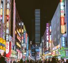 夜晚，东京新宿繁忙的街道上，色彩缤纷的霓虹灯和充满活力的城市生活照亮了整条街