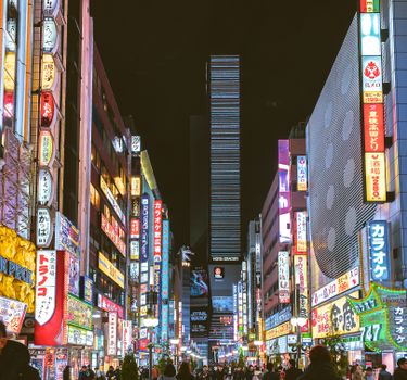 夜晚，东京新宿繁忙的街道上，色彩缤纷的霓虹灯和充满活力的城市生活照亮了整条街