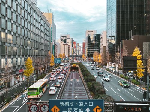 Free Vibrant cityscape of downtown Tokyo featuring busy traffic and autumn trees. Stock Photo