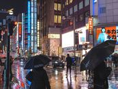 雨夜的东京街头，霓虹灯光映照在潮湿的人行道上，充满活力