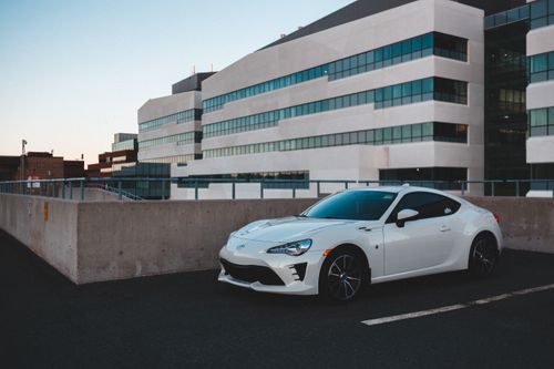 Free Modern white automobile parked on asphalt with marking line near local business center Stock Photo