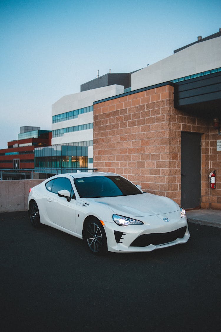 Contemporary Car With Luminous Headlights Near Brick Building