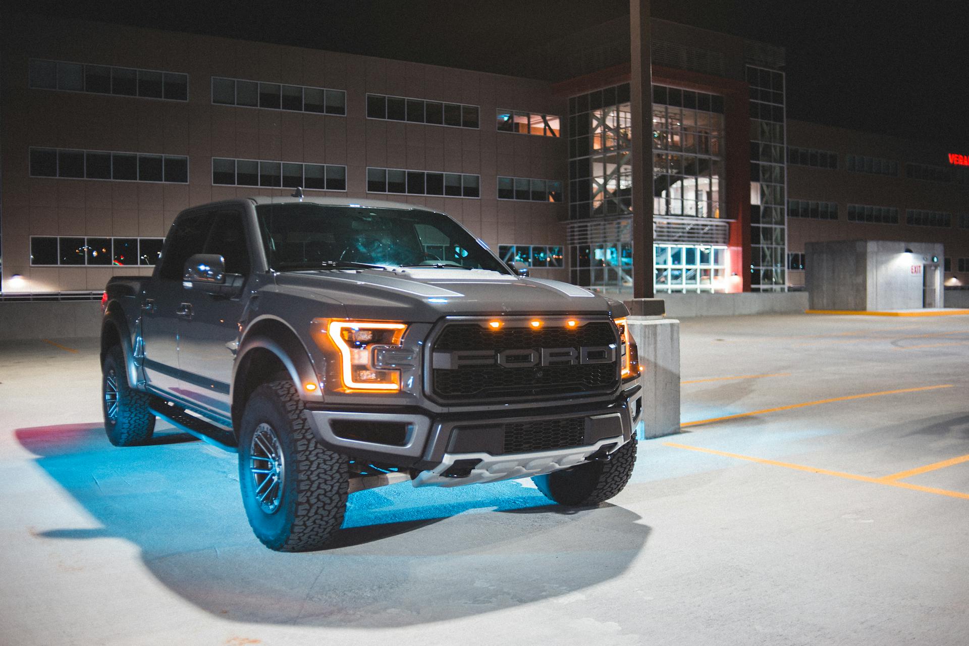 A sleek gray pickup truck parked in an urban area at night, showcasing modern design and headlights.