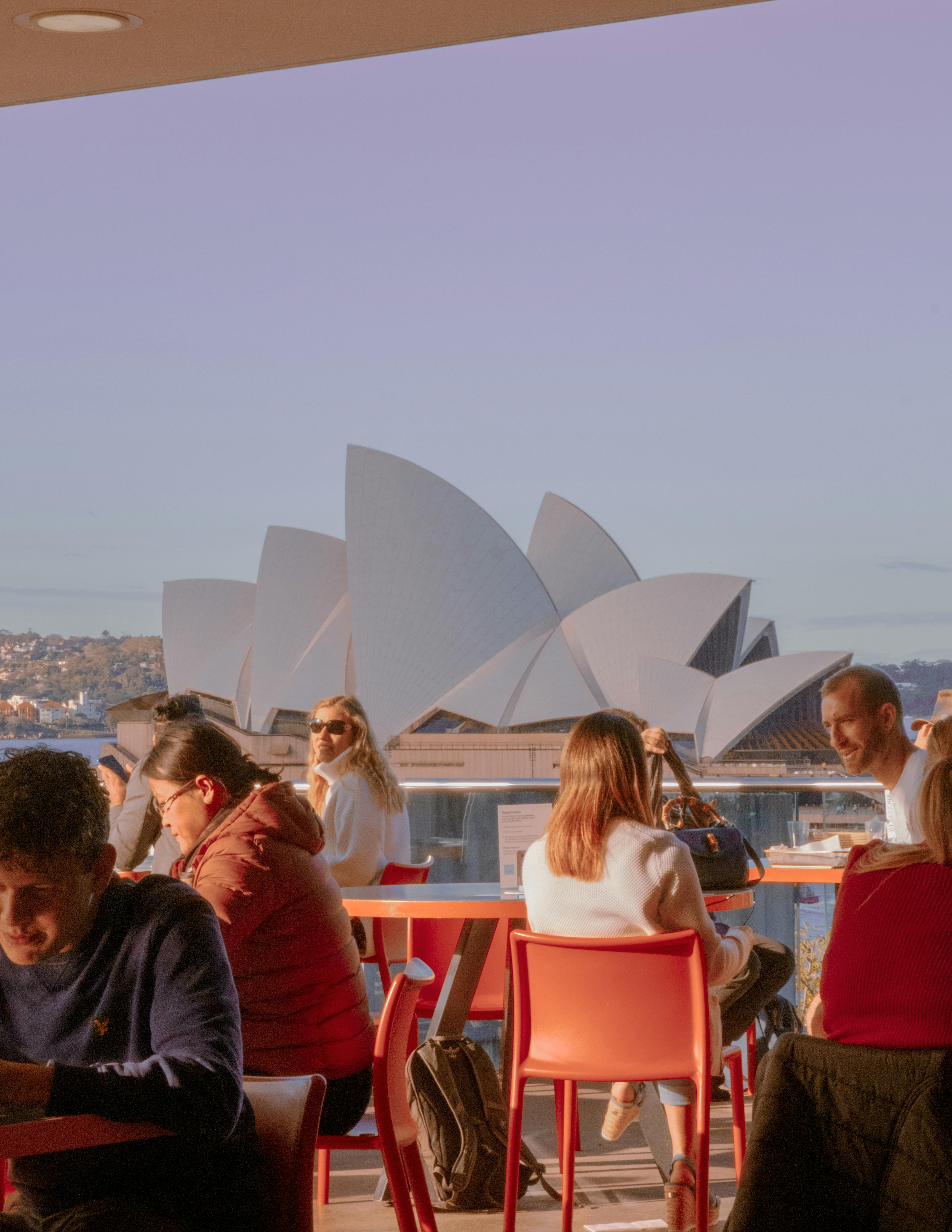 People enjoying a coffee with a view of the Sydney Opera House in Australia.