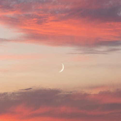 Bright white crescent between fluffy clouds