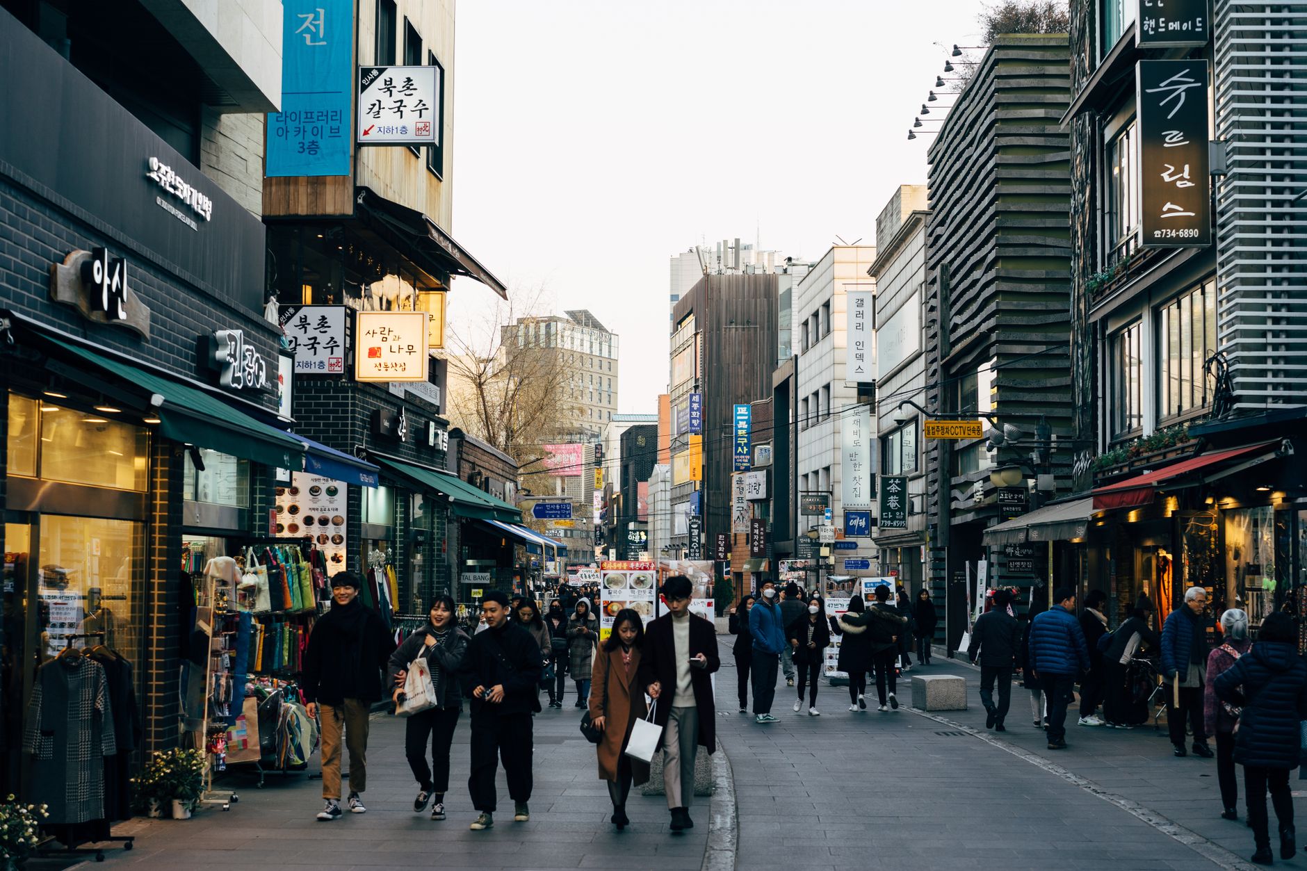 Lively shopping street in Seoul with people walking, shops, and vibrant city life.