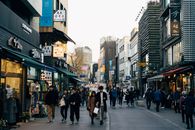首尔热闹的购物街上，人们步行穿梭，商店林立，充满了活力的城市生活