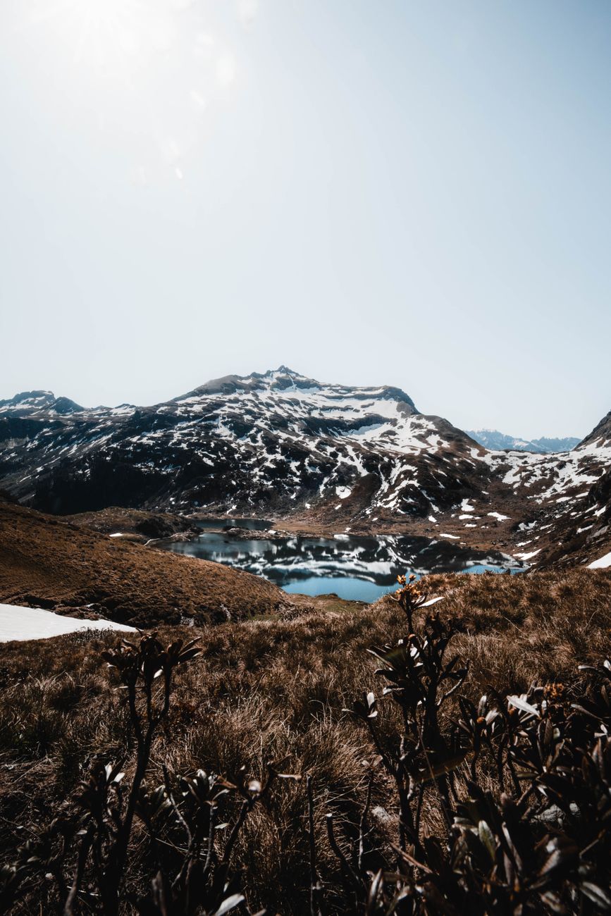 Breathtaking view of the Swiss Alps with a serene lake reflecting the snow-capped peaks under clear skies.