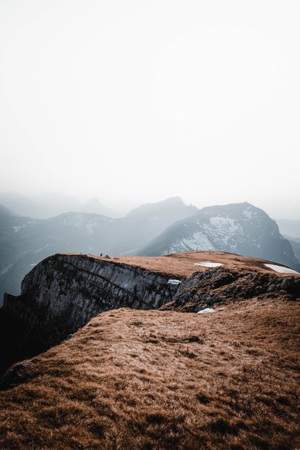 Breathtaking view of a foggy Alpine landscape in Switzerland, showcasing rugged cliffs and serene beauty.