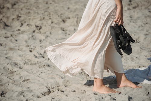Free Woman in White Dress Walking on Sand Stock Photo