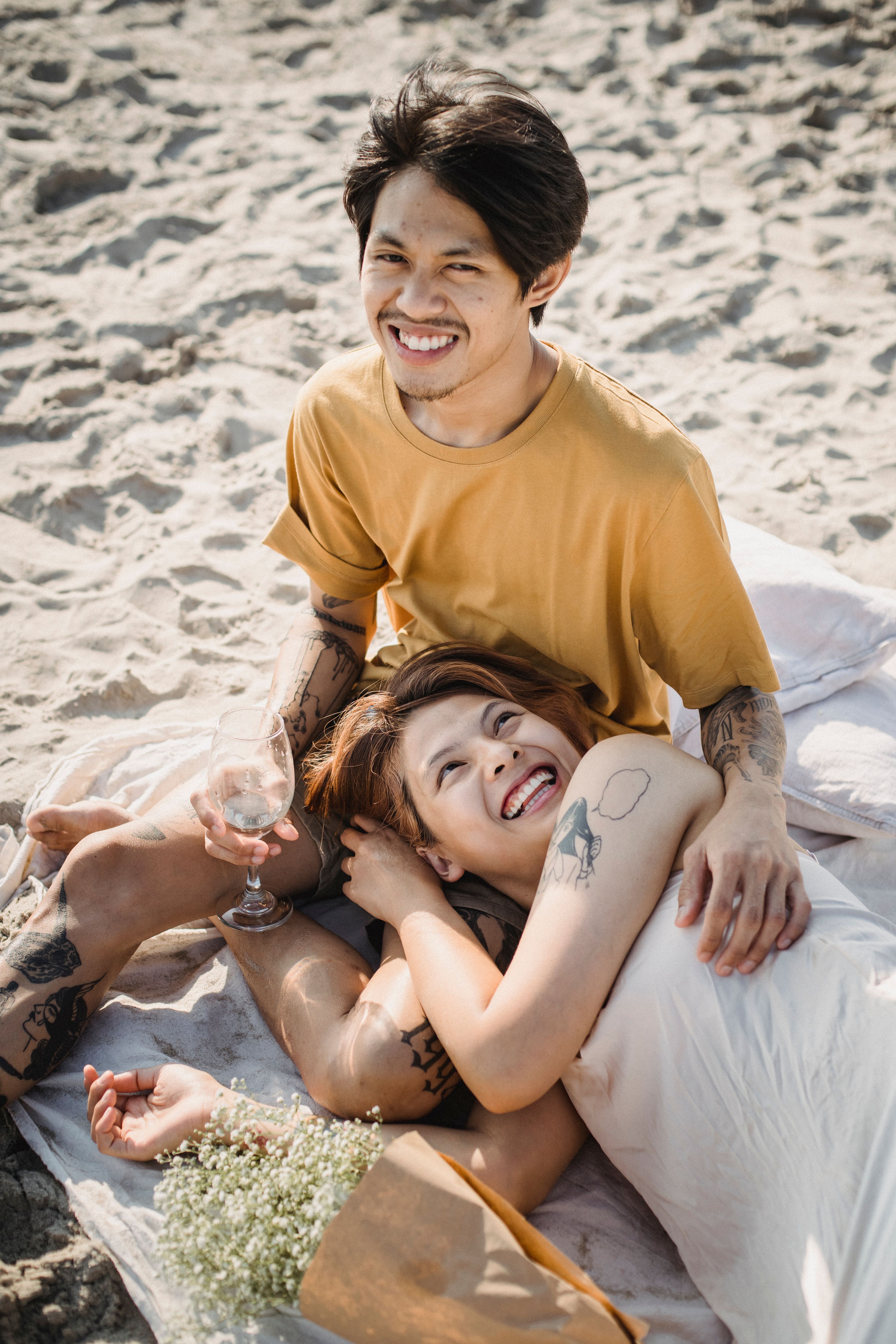 Happy couple relaxing on the beach, enjoying a sunny day and a glass of wine.