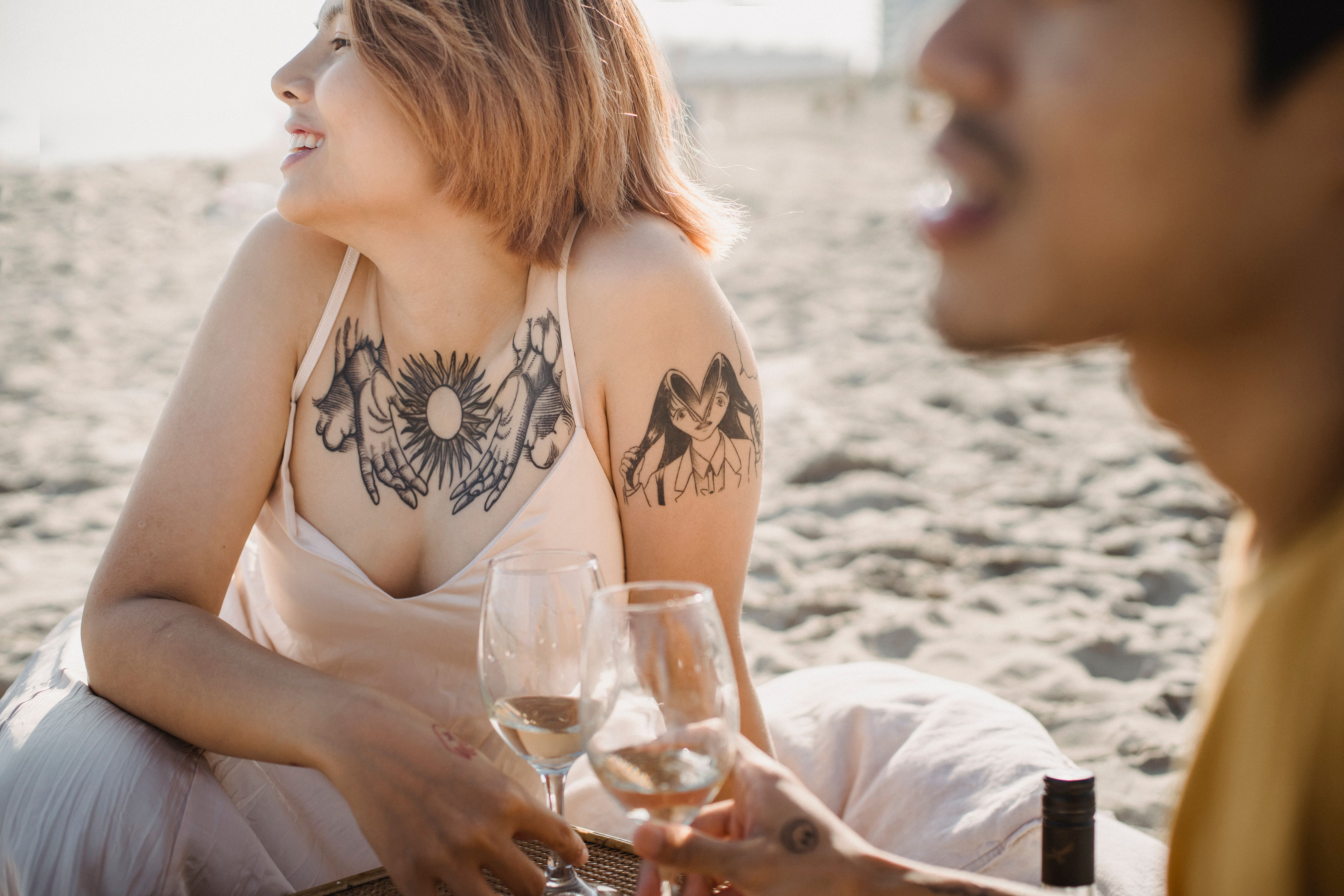 Two adults enjoying wine at the beach, capturing a moment of relaxation and leisure.