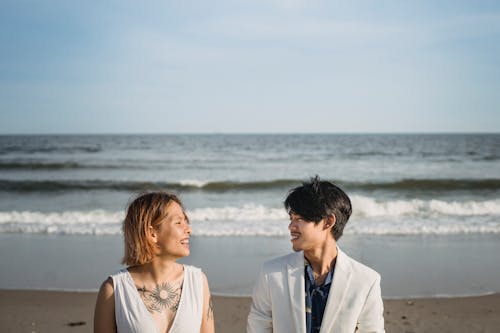 Free Man and Woman Standing on the Beach Stock Photo