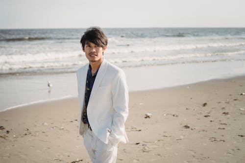 Man in White Suit Standing on Beach