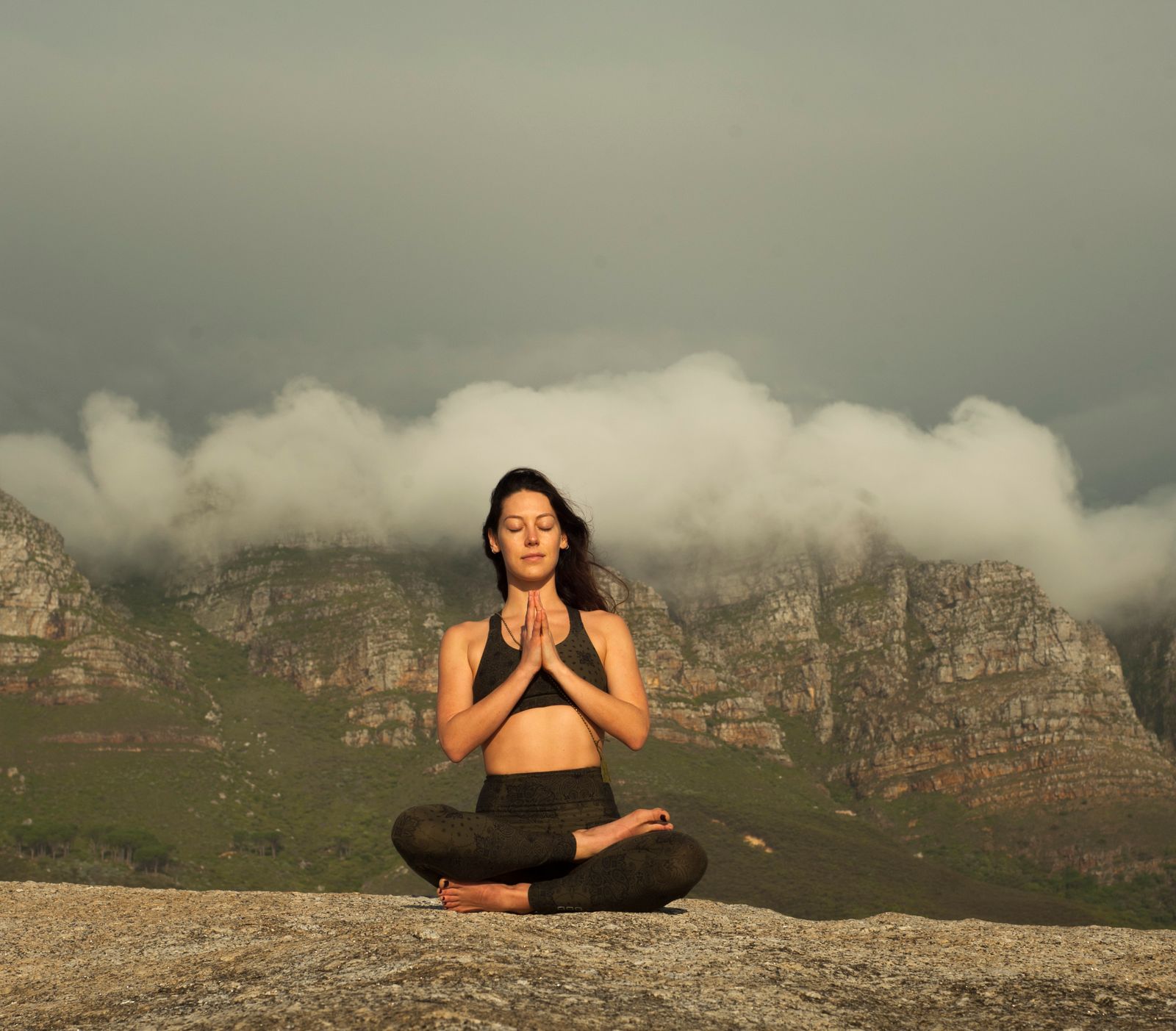 Person meditating outdoors surrounded by nature, eyes closed in stillness