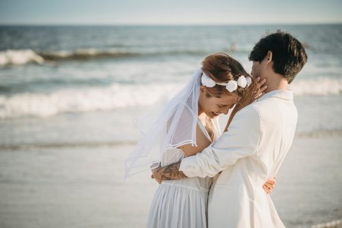 Free A joyful bride and groom embracing by the seashore, symbolizing love and romance. Stock Photo