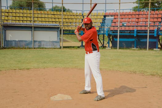 An African American man in a baseball uniform poised to hit on a baseball field.