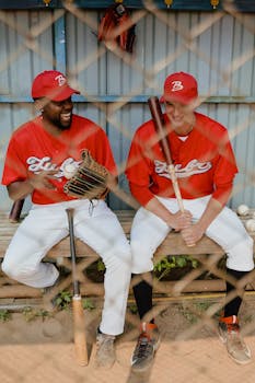 两名身穿制服的棒球运动员在长凳上轻松地分享了一段时光