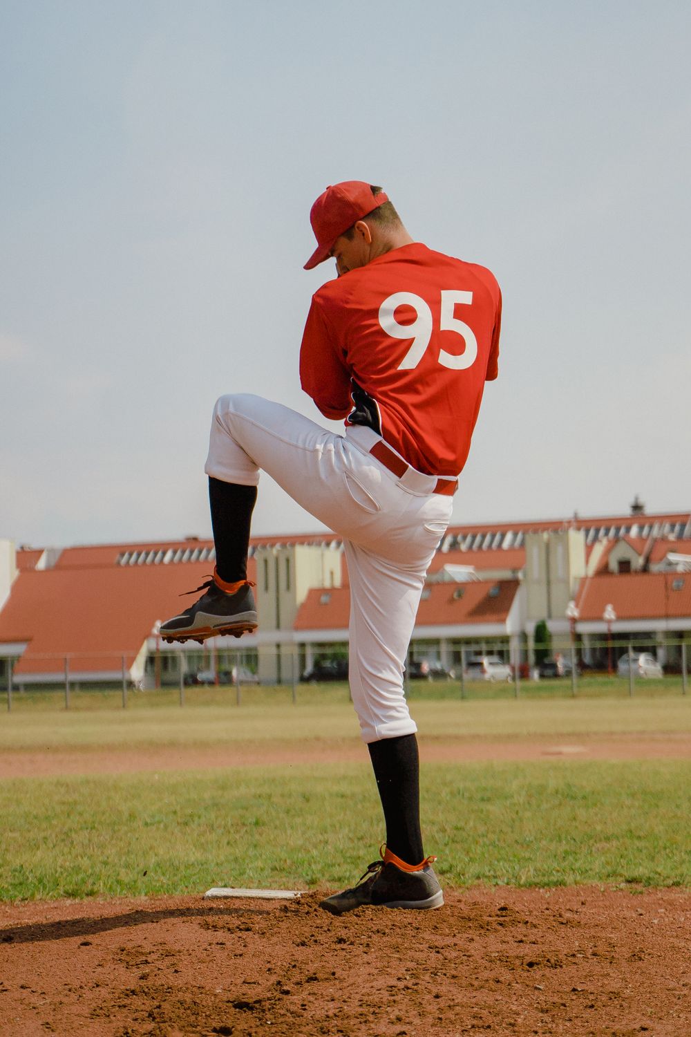 Falcons pitcher in a red jersey in mid windup on the mound