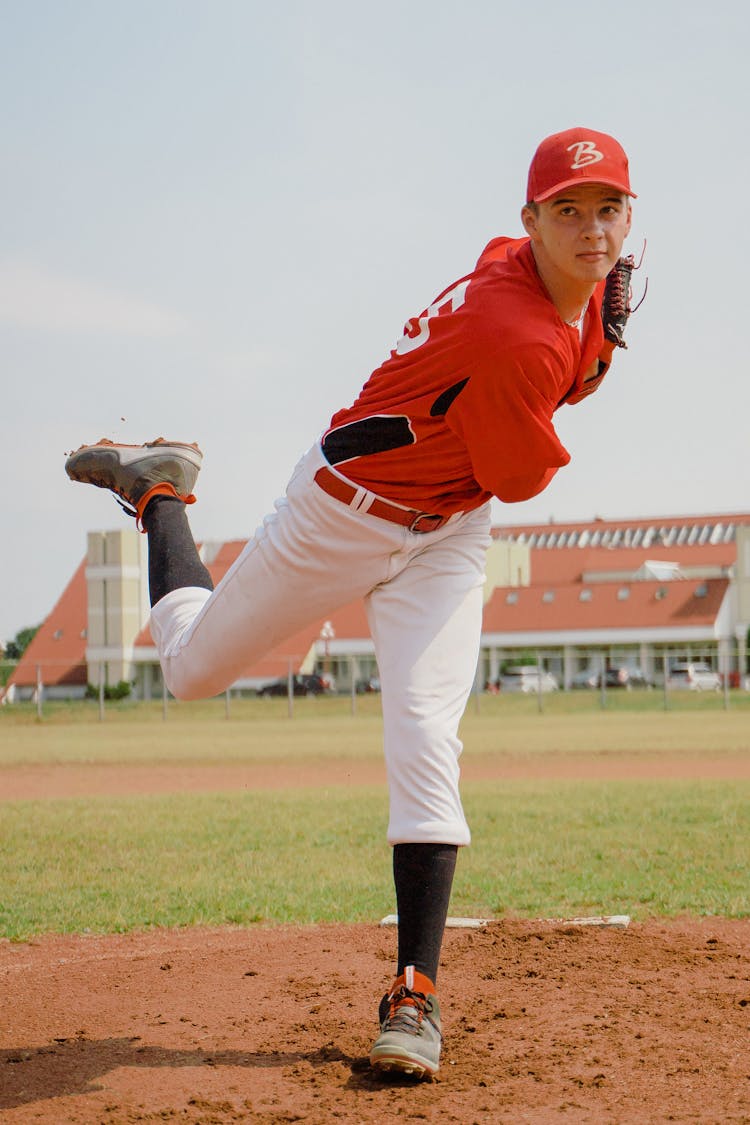 Man In Red Jersey Shirt And White Pants Throwing A Ball