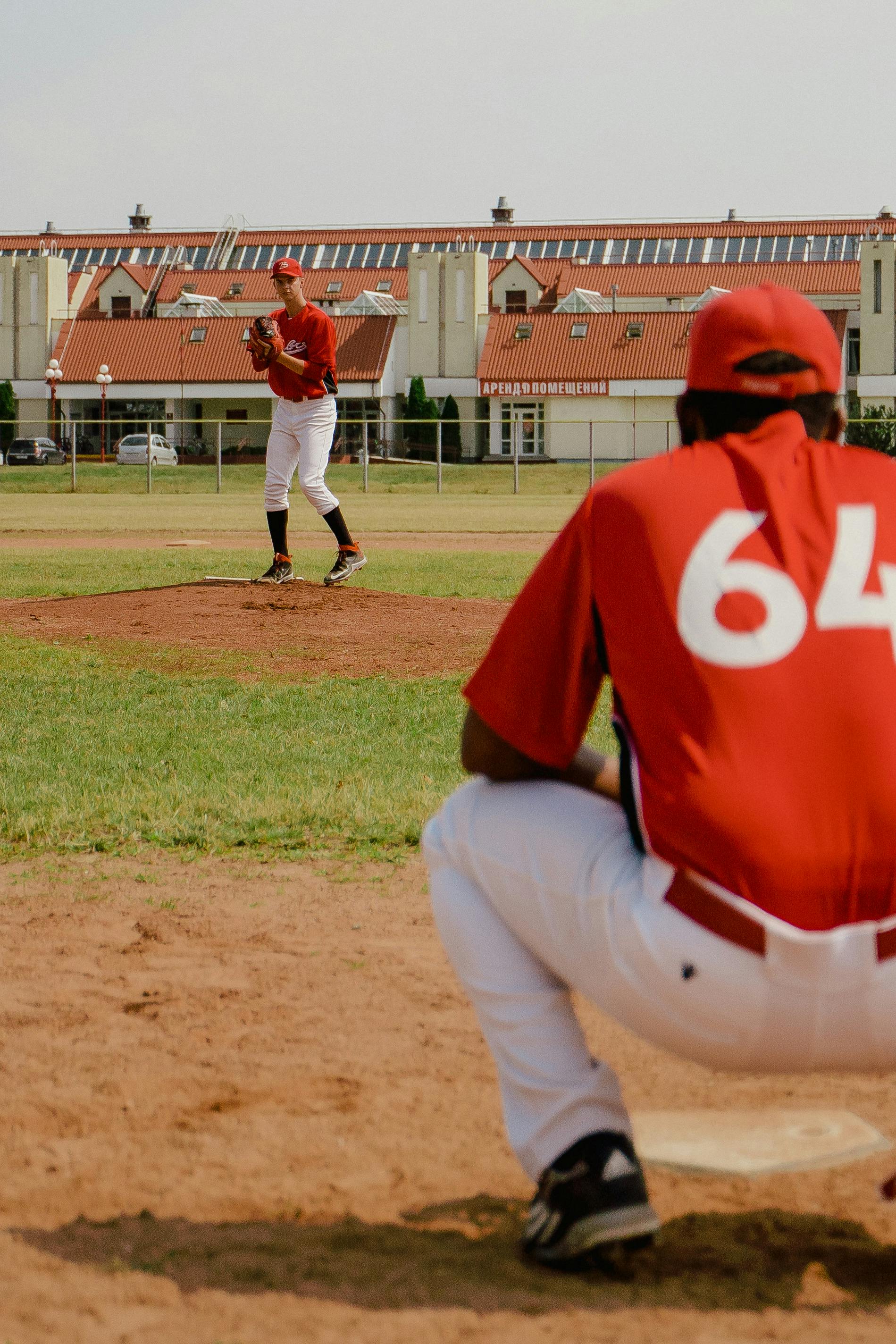 man in red jersey shirt and white pants standing on baseball field