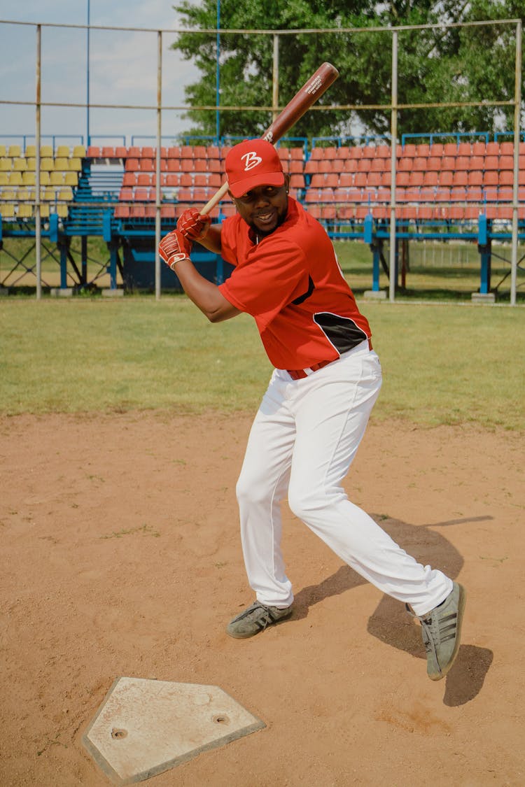 Man In Red Baseball Cap Swinging A Baseball Bat