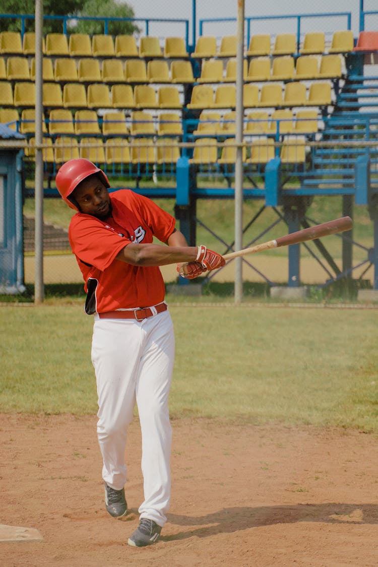 Man In Red Baseball Jersey Swinging A Baseball Bat