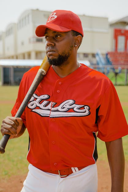 Man in Red Baseball Jersey Holding a Baseball Bat · Free Stock Photo