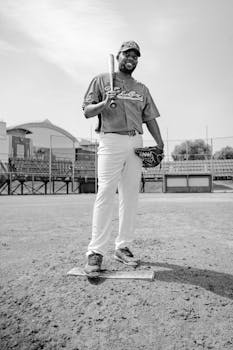 Black and white portrait of an athlete standing confidently on a baseball field.