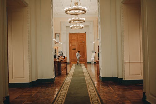 Interior of old building with high decorated ceiling and massive wooden doorway in corridor