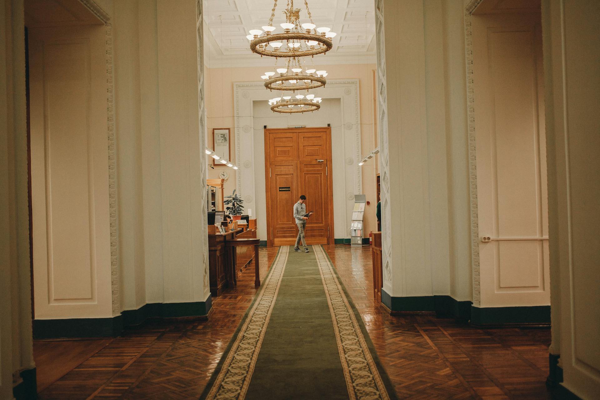 Interior of old building with high decorated ceiling and massive wooden doorway in corridor