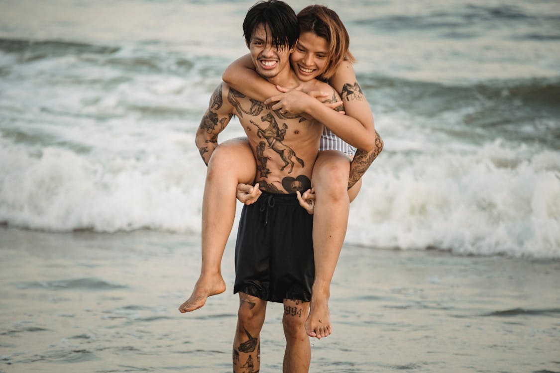 Free Photo  Man giving piggyback ride to woman on the beach