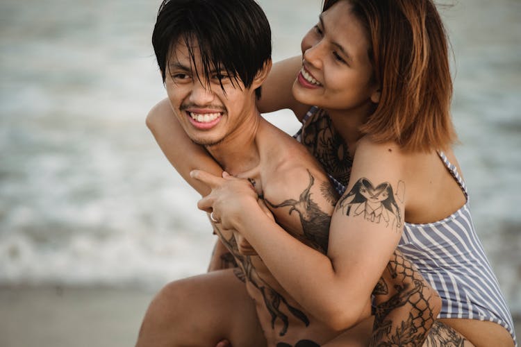 Smiling Couple In Swimsuits Hugging On Beach