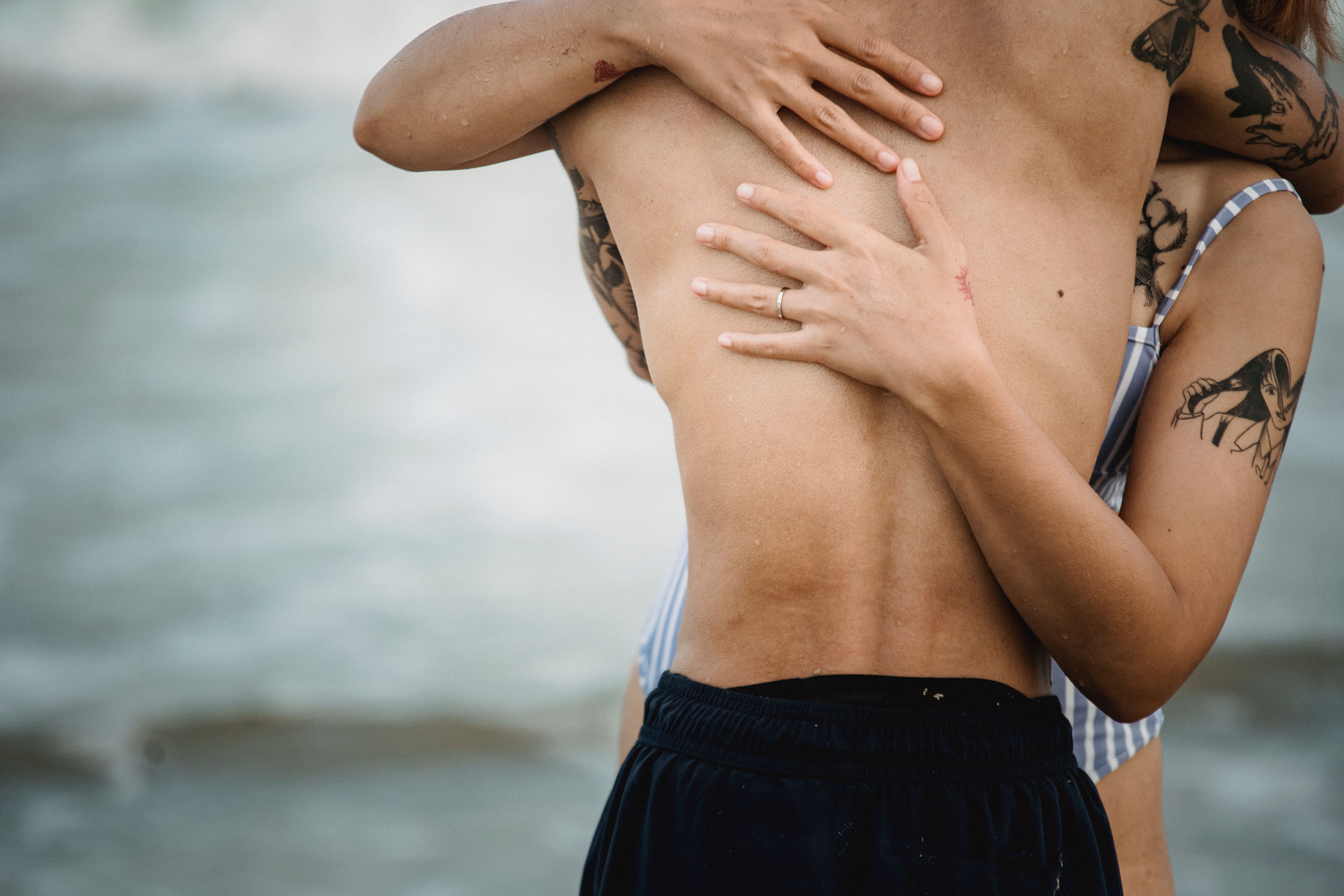 Young couple enjoying beach day with visible temporary tattoo stickers, embodying fun casual lifestyle fashion.